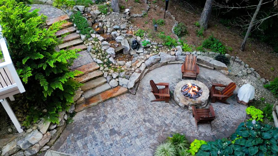 Fire pit and paver patio combination with boulder wall and stone steps designed and installed for Kennesaw, Georgia homeowner.