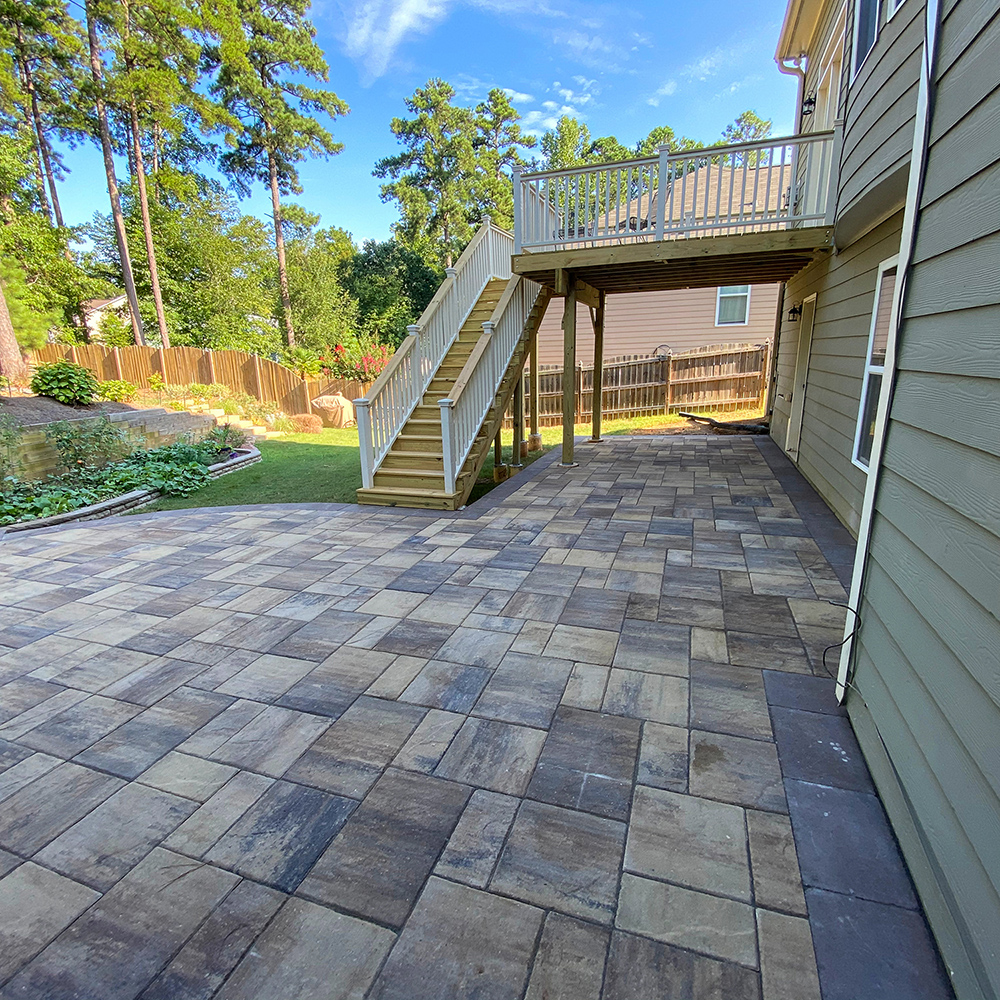 Deck descending to new paver patio space designed and installed for Marietta, Georgia homeowner.